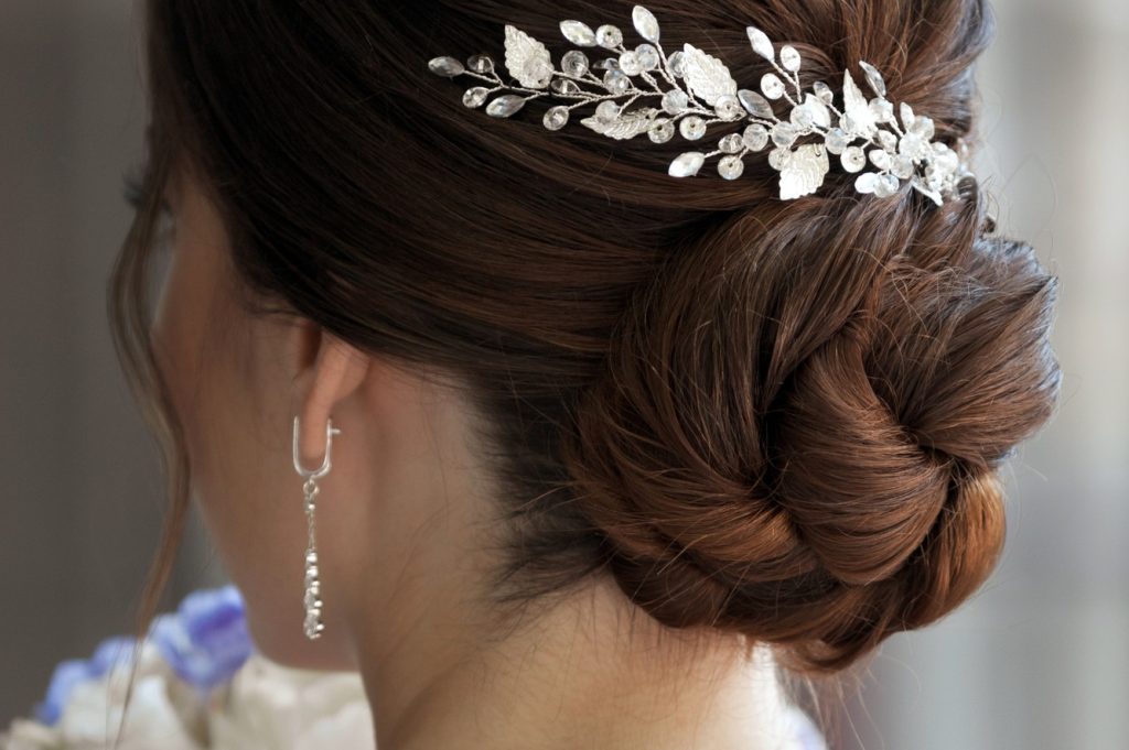 Close-up bride frome back with elegance wedding updo hairstyle for medium brown hair with hairpin